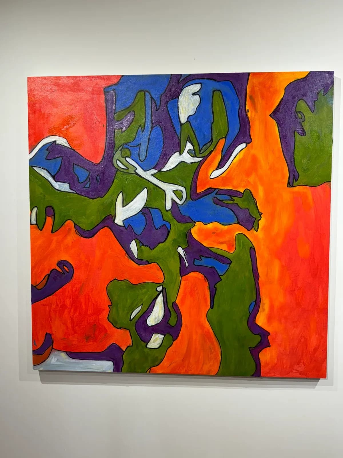 An abstract painting by Steven W. Miller with vivid orange, blue and olive forms, displayed on a gallery wall
